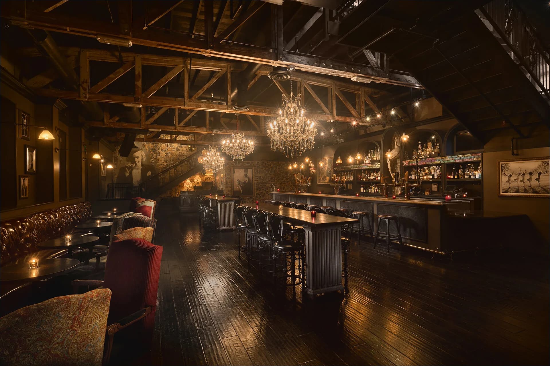 The wood-paneled main room at Commonwealth with chandeliers and a long bar